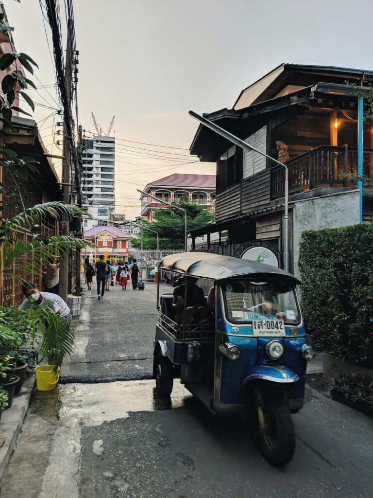 pexels-photo-1682748-1682748 Bangkok street scene featuring a tuk-tuk amidst traditional and modern architecture.