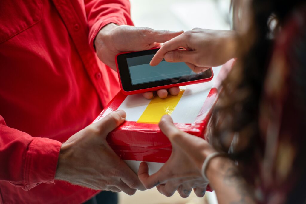 pexels-photo-6721907-6721907 Hands exchanging a package with an electronic signature for contactless delivery.